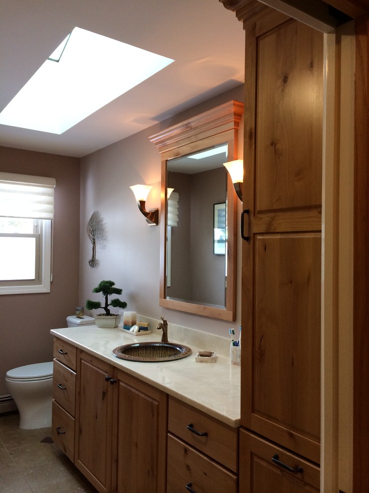 Inspiration for a mid-sized country master bathroom in Boston with a drop-in sink, raised-panel cabinets, medium wood cabinets, marble benchtops, a two-piece toilet, beige tile, beige walls, porcelain floors, a corner shower, stone tile, beige floor and a hinged shower door.