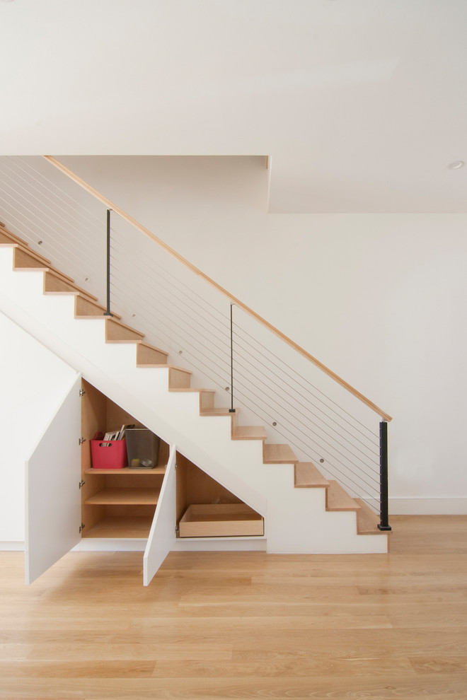 This is an example of a mid-sized modern wood straight staircase in New York with wood risers and cable railing.