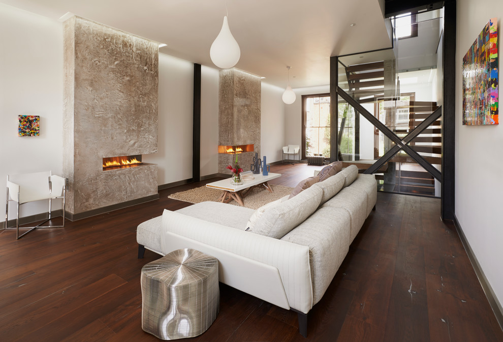 This is an example of a contemporary living room in London with dark hardwood floors, a two-sided fireplace, a plaster fireplace surround, white walls and no tv.