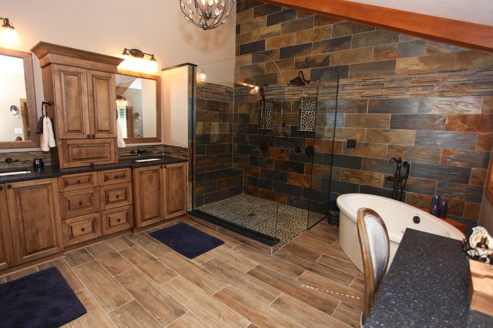 Freestanding bathtub - large rustic master slate tile brown floor freestanding bathtub idea in Indianapolis with brown cabinets, beige walls and an undermount sink