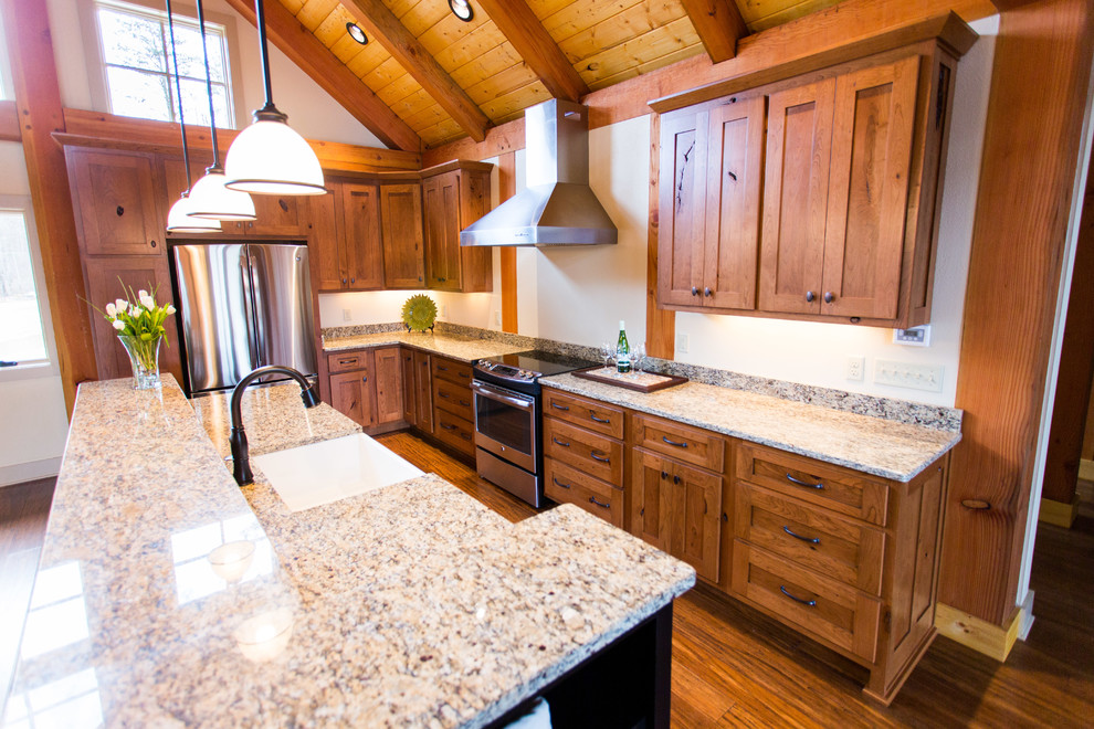 Inspiration for a large rustic l-shaped medium tone wood floor open concept kitchen remodel with a farmhouse sink, shaker cabinets, medium tone wood cabinets, granite countertops, stainless steel appliances and an island