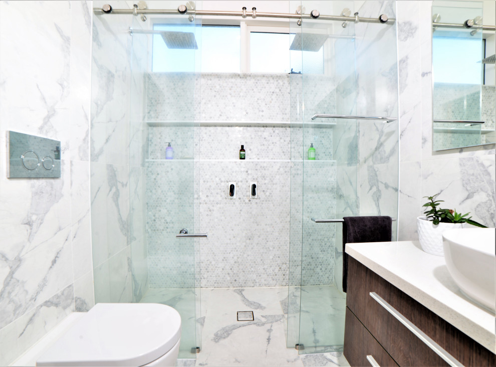 This is an example of a mid-sized midcentury master bathroom in Melbourne with a drop-in tub, a double shower, a one-piece toilet, white tile, porcelain tile, white walls, porcelain floors, a vessel sink, recycled glass benchtops, white floor, a sliding shower screen, white benchtops, a single vanity and a floating vanity.