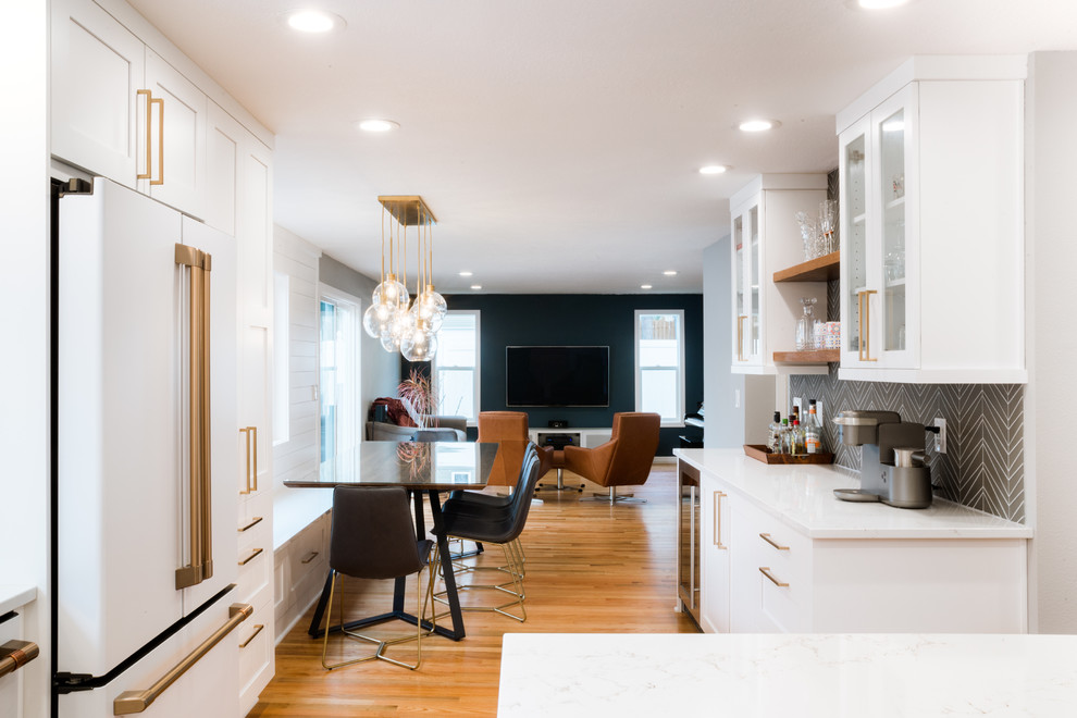 This is an example of a mid-sized modern l-shaped eat-in kitchen in Portland with a farmhouse sink, shaker cabinets, white cabinets, quartz benchtops, white splashback, marble splashback, white appliances, light hardwood floors, with island and white benchtop.