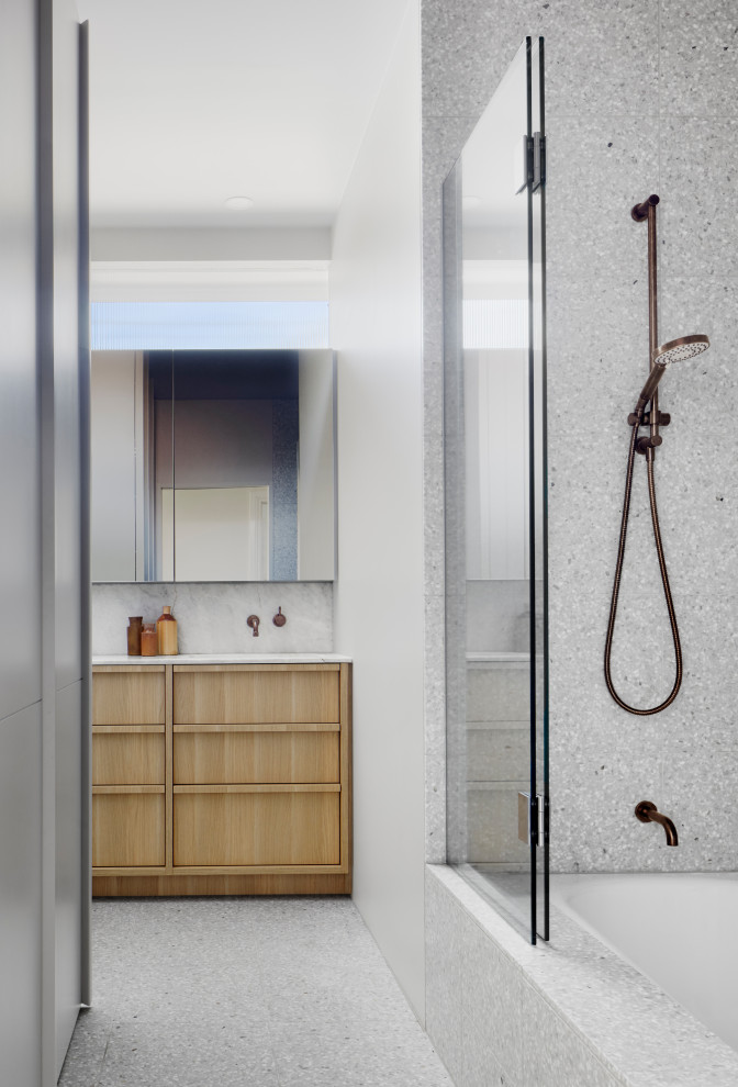 This is an example of a modern bathroom in Melbourne with flat-panel cabinets, light wood cabinets, an alcove tub, a shower/bathtub combo, gray tile, white walls, grey floor, a hinged shower door, white benchtops and a built-in vanity.