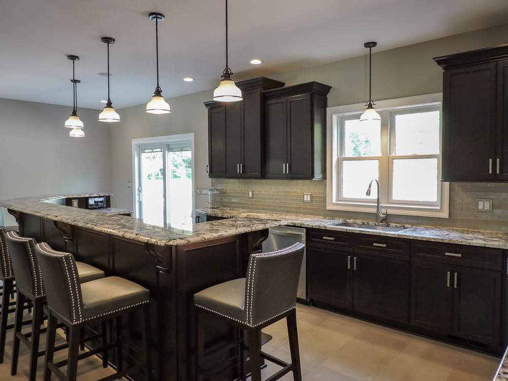 Large transitional u-shaped porcelain tile and beige floor eat-in kitchen photo in Bridgeport with an undermount sink, raised-panel cabinets, dark wood cabinets, granite countertops, green backsplash, glass tile backsplash, stainless steel appliances, an island and brown countertops