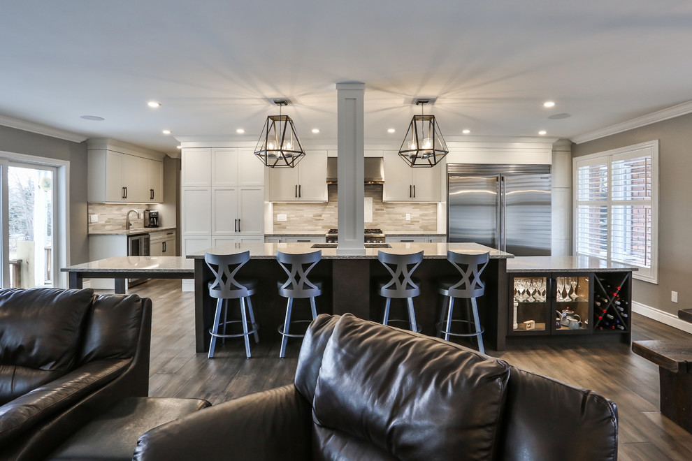 Large transitional medium tone wood floor and gray floor open concept kitchen photo in Toronto with an undermount sink, shaker cabinets, white cabinets, quartz countertops, gray backsplash, marble backsplash, stainless steel appliances, an island and multicolored countertops