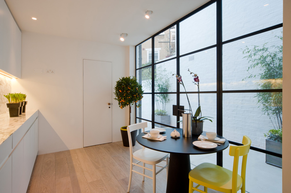 Design ideas for a mid-sized contemporary kitchen/dining combo in London with light hardwood floors.