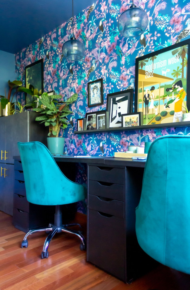 Mid-sized island style freestanding desk medium tone wood floor craft room photo in San Diego with blue walls