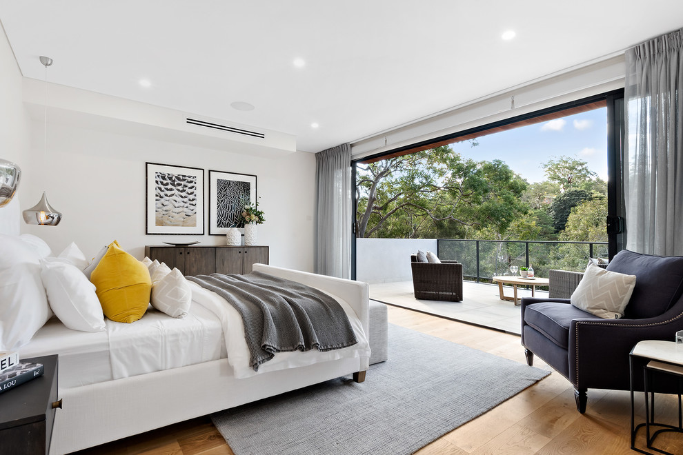 Contemporary bedroom in Sydney with white walls, medium hardwood floors and brown floor.
