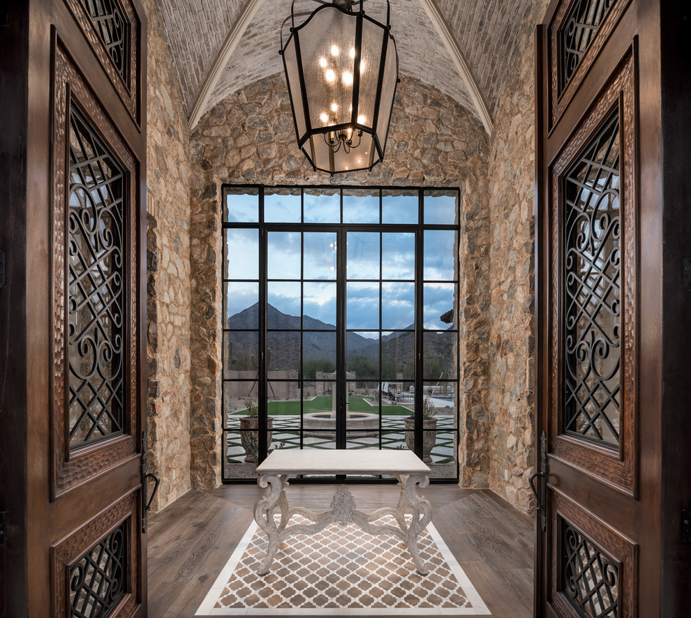 Example of a huge mountain style dark wood floor, multicolored floor, shiplap ceiling and brick wall foyer design in Phoenix with multicolored walls and a brown front door