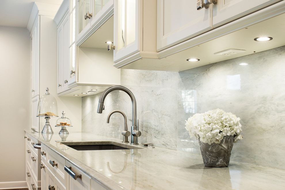 Kitchen - large transitional single-wall medium tone wood floor and brown floor kitchen idea in Denver with an undermount sink, recessed-panel cabinets, white cabinets, white backsplash, stone slab backsplash, stainless steel appliances and an island
