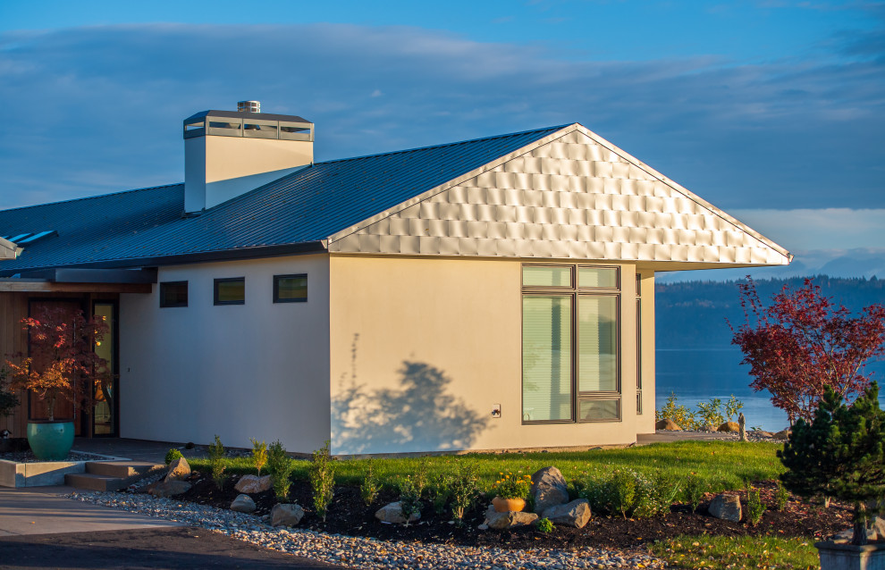 Modelo de fachada de casa blanca actual de una planta con revestimiento de estuco, tejado a dos aguas y tejado de metal
