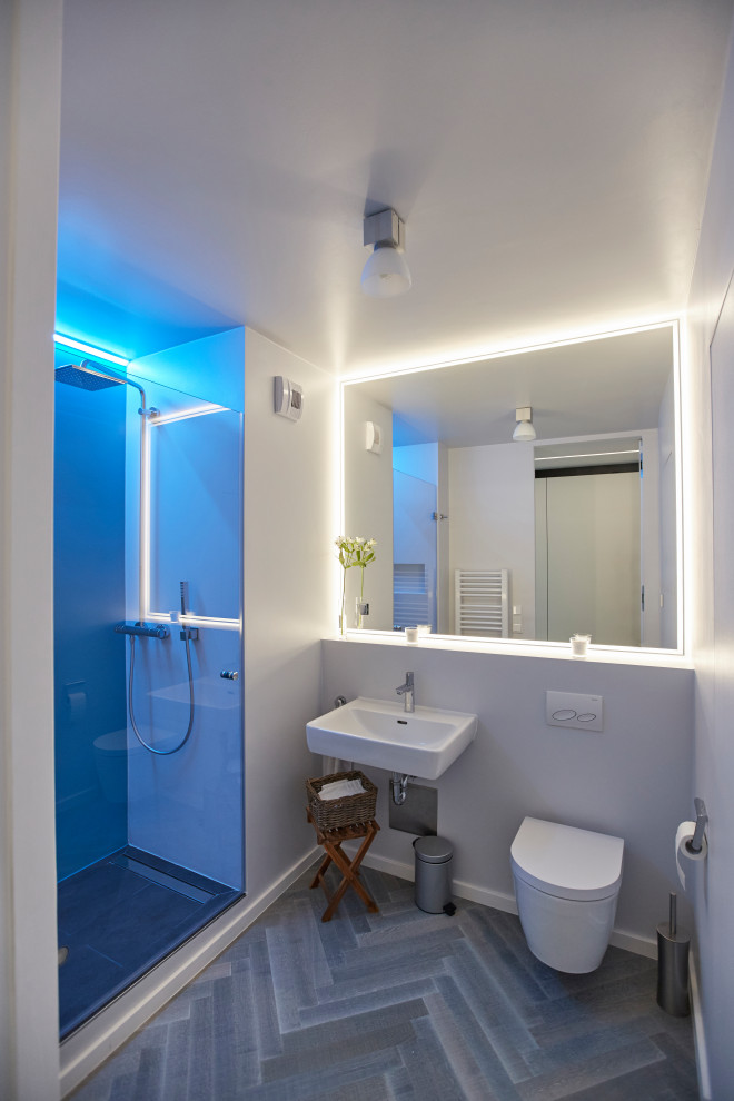 Idéer för små funkis vitt en-suite badrum, med en vägghängd toalettstol, vita väggar, målat trägolv, grått golv, en kantlös dusch, ett väggmonterat handfat och dusch med gångjärnsdörr