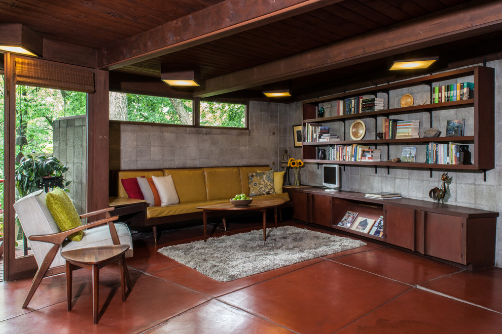 Photo of a midcentury family room in Other with a library, no fireplace, concrete floors and brown floor.