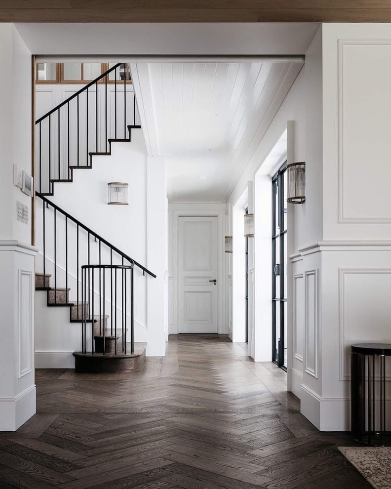 This is an example of a traditional entry hall in New York with white walls, dark hardwood floors, a double front door, a glass front door and brown floor.