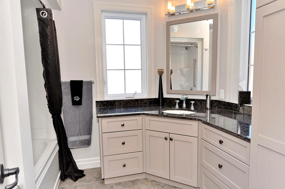 Photo of a large contemporary master bathroom in Toronto with an undermount sink, recessed-panel cabinets, white cabinets, granite benchtops, an alcove tub, a two-piece toilet, beige tile, ceramic tile, grey walls and ceramic floors.
