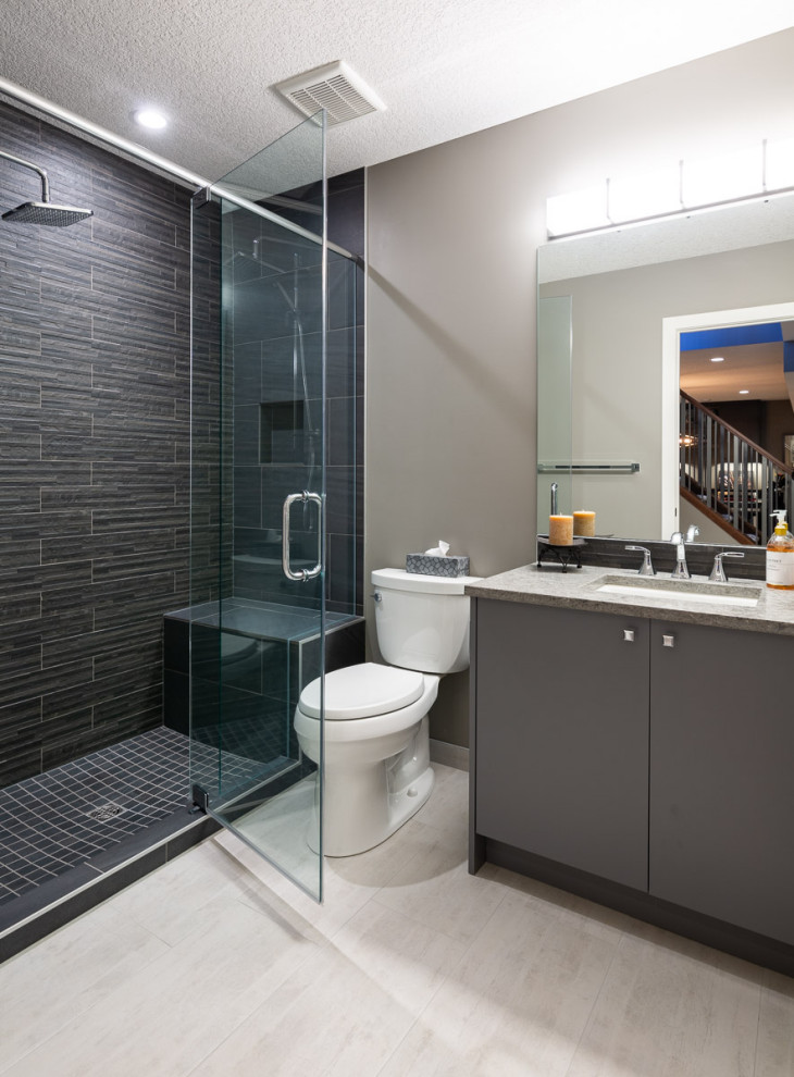 This is an example of a mid-sized contemporary 3/4 bathroom in Calgary with flat-panel cabinets, grey cabinets, an alcove shower, a two-piece toilet, grey walls, vinyl floors, an undermount sink, engineered quartz benchtops, beige floor, a hinged shower door, multi-coloured benchtops, a niche, a shower seat, a single vanity and a freestanding vanity.
