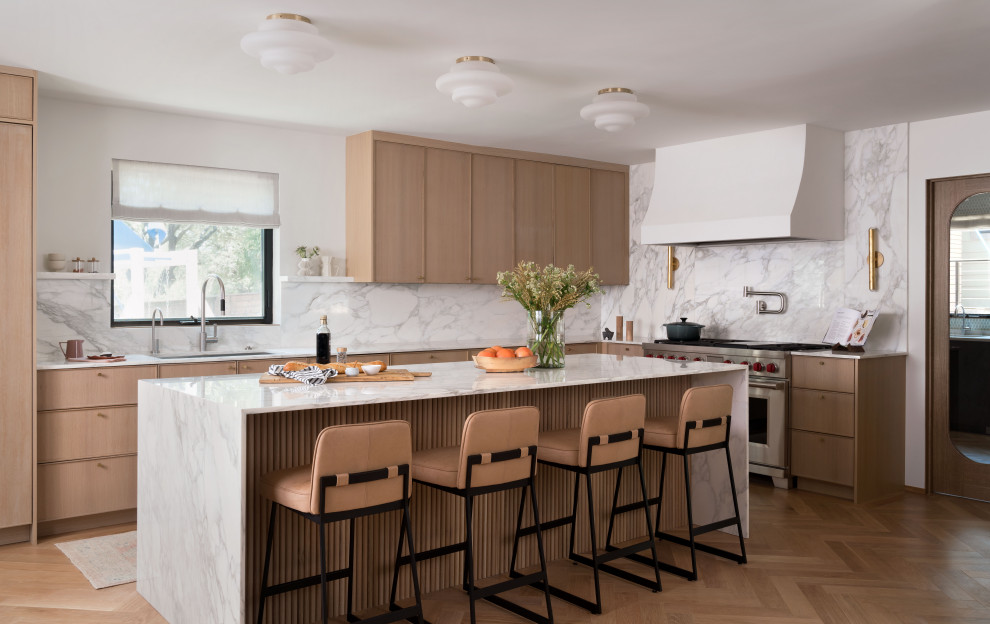 Klassische Küche in L-Form mit Unterbauwaschbecken, hellen Holzschränken, Küchengeräten aus Edelstahl, hellem Holzboden und Kücheninsel in Austin