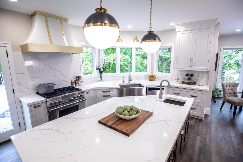 Inspiration for a transitional medium tone wood floor and brown floor eat-in kitchen remodel with a farmhouse sink, shaker cabinets, white cabinets, quartz countertops, white backsplash, quartz backsplash, stainless steel appliances, two islands and white countertops