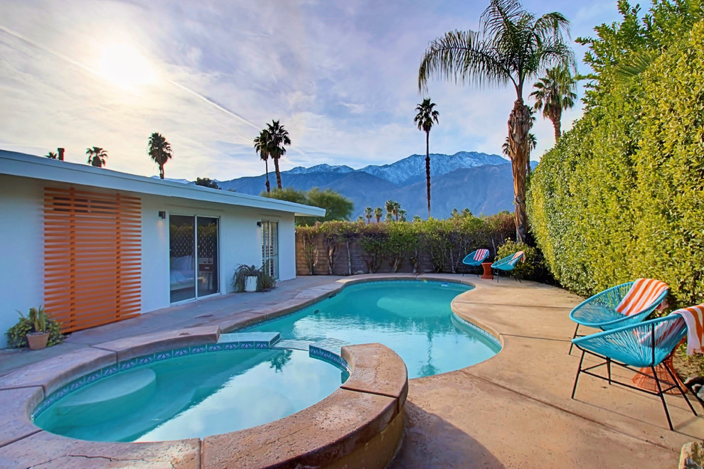 Large midcentury side yard kidney-shaped pool in Phoenix with a hot tub and concrete slab.