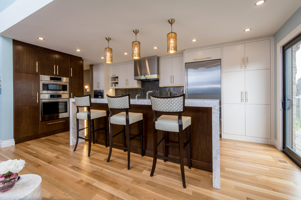 Large transitional l-shaped light wood floor eat-in kitchen photo in Toronto with an undermount sink, flat-panel cabinets, white cabinets, marble countertops, black backsplash, matchstick tile backsplash, stainless steel appliances and an island
