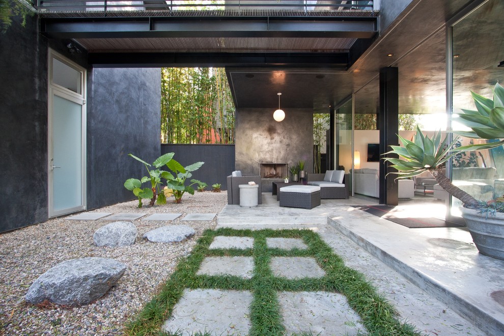 This is an example of a mid-sized contemporary courtyard patio in Los Angeles with with fireplace, concrete slab and a roof extension.