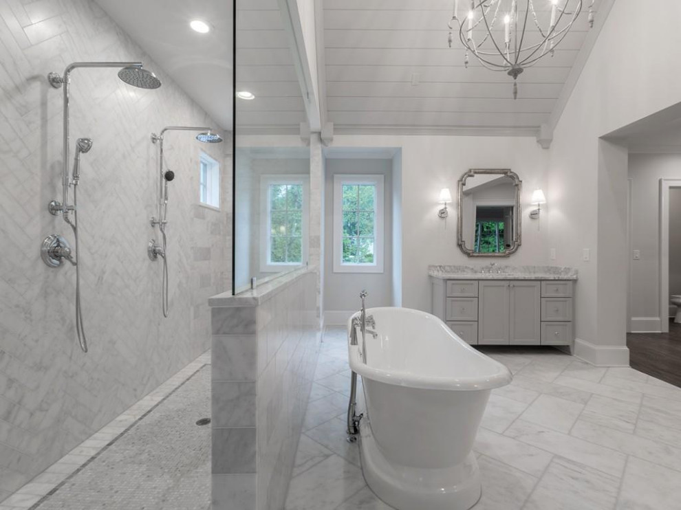 Expansive transitional master bathroom in Atlanta with shaker cabinets, grey cabinets, a freestanding tub, an open shower, white tile, marble, grey walls, marble floors, an undermount sink, marble benchtops, white floor, an open shower, white benchtops, an enclosed toilet, a freestanding vanity and vaulted.