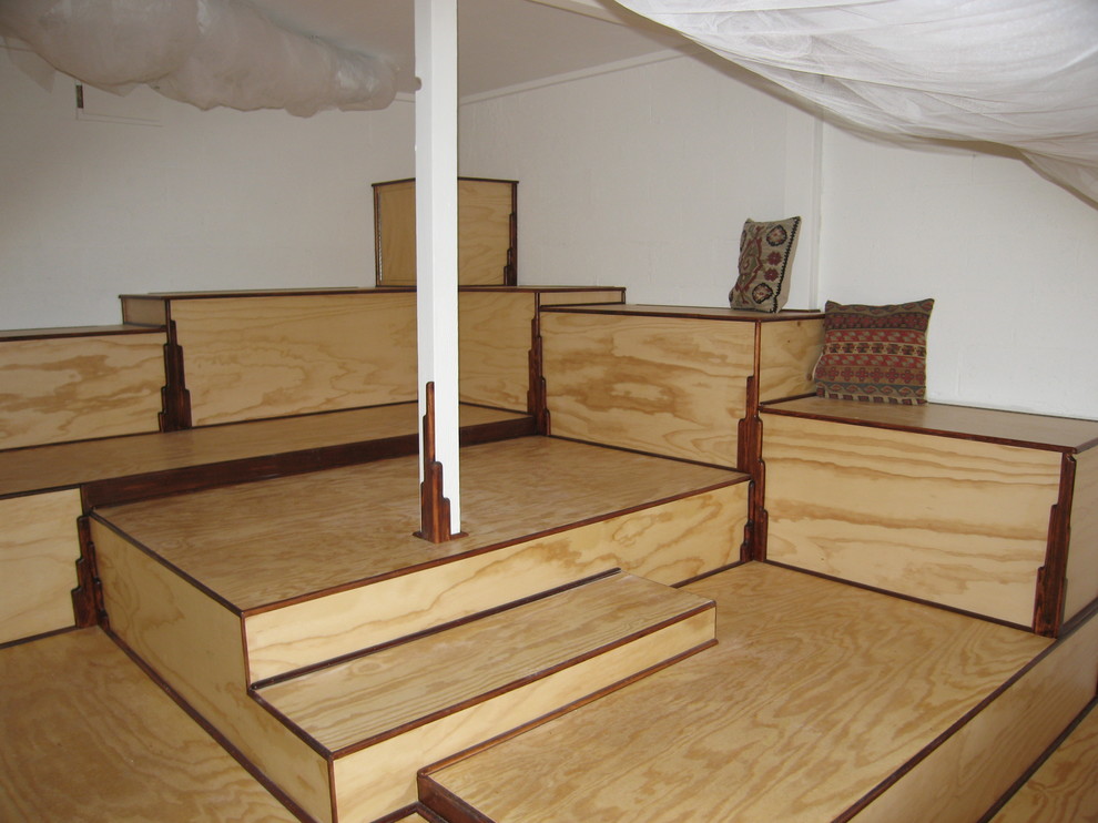 This is an example of a kids' room in Other with plywood floors.