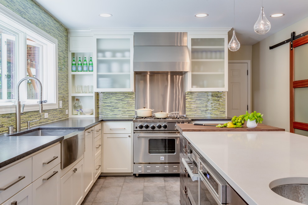 Transitional l-shaped kitchen in Seattle with a farmhouse sink, shaker cabinets, white cabinets, multi-coloured splashback, matchstick tile splashback, stainless steel appliances and with island.