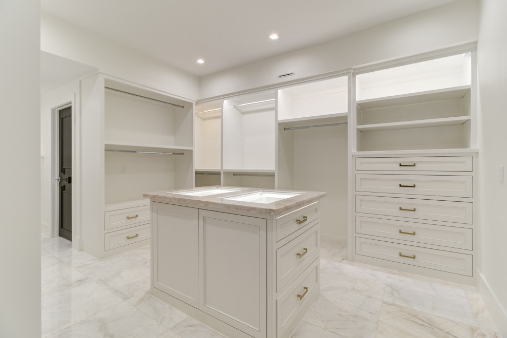 Design ideas for a large transitional gender-neutral walk-in wardrobe in Houston with white cabinets, marble floors and white floor.