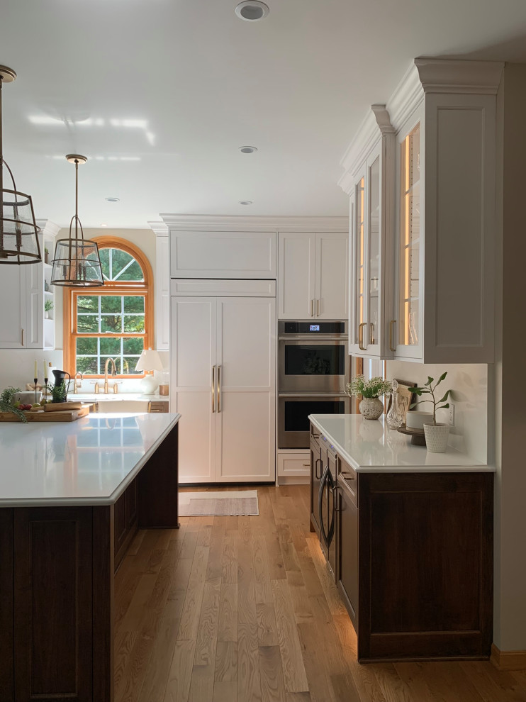 Light wood floor kitchen photo with a double-bowl sink, shaker cabinets, white cabinets, quartz countertops, quartz backsplash, paneled appliances and an island