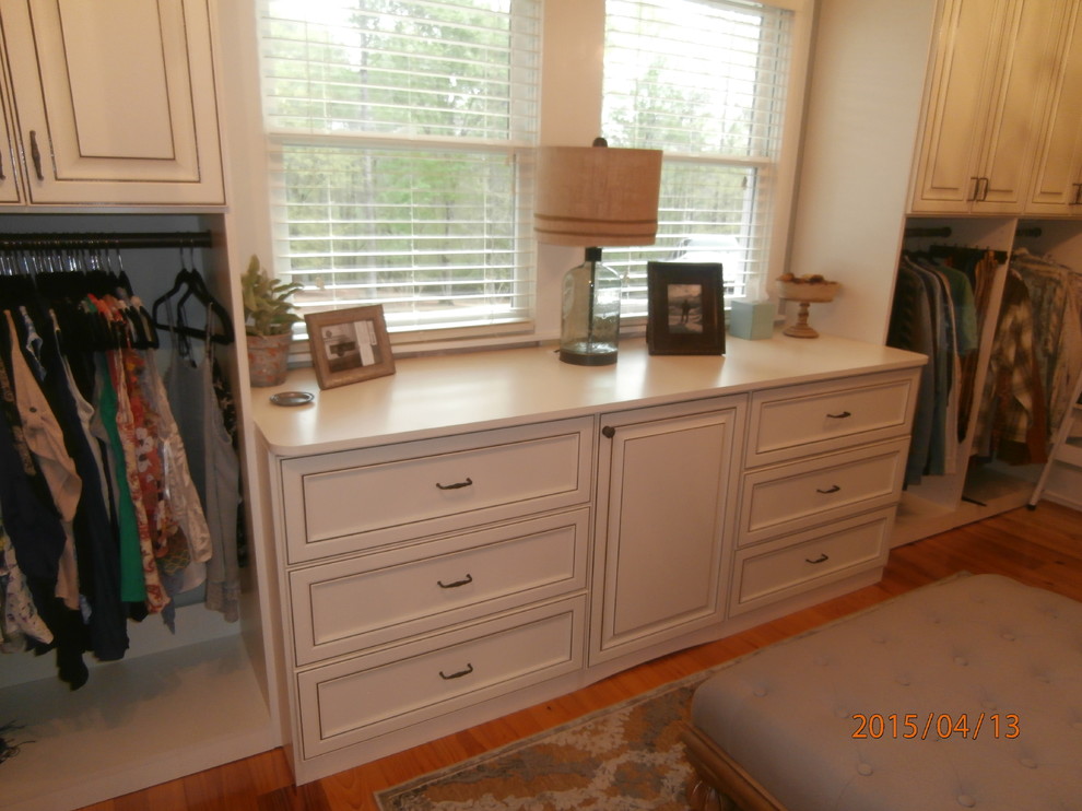 Mid-sized traditional women's dressing room in Atlanta with raised-panel cabinets, distressed cabinets and light hardwood floors.