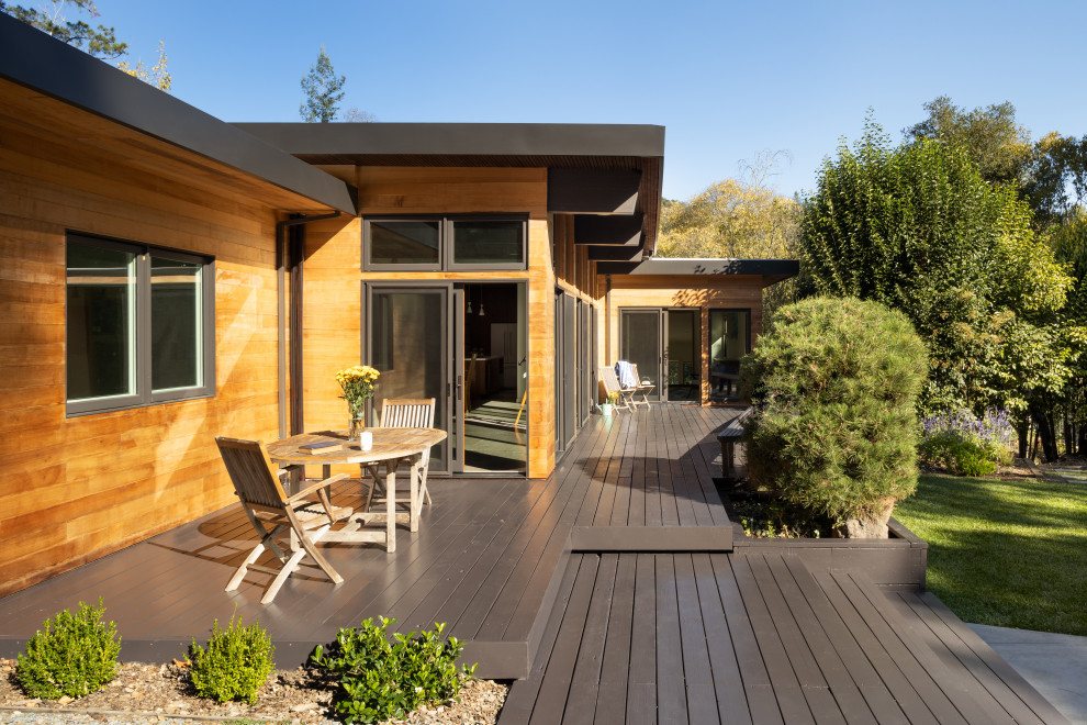 Idée de décoration pour une façade de maison design en bois et bardage à clin de plain-pied avec un toit plat, un toit en métal et un toit marron.
