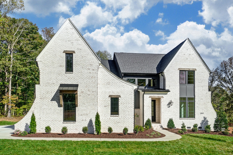 Großes, Zweistöckiges Einfamilienhaus mit gestrichenen Ziegeln, weißer Fassadenfarbe, Satteldach, Schindeldach, schwarzem Dach und Wandpaneelen in Charlotte