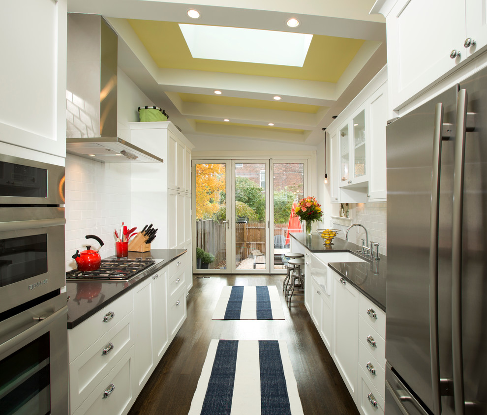 Design ideas for a mid-sized transitional galley separate kitchen in DC Metro with subway tile splashback, stainless steel appliances, a farmhouse sink, white cabinets, granite benchtops, white splashback, dark hardwood floors, no island and shaker cabinets.