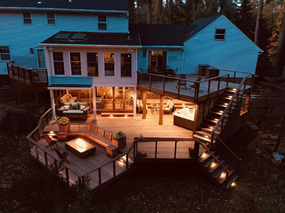 Photo of an expansive transitional backyard and ground level deck in Other with an outdoor shower, no cover and cable railing.