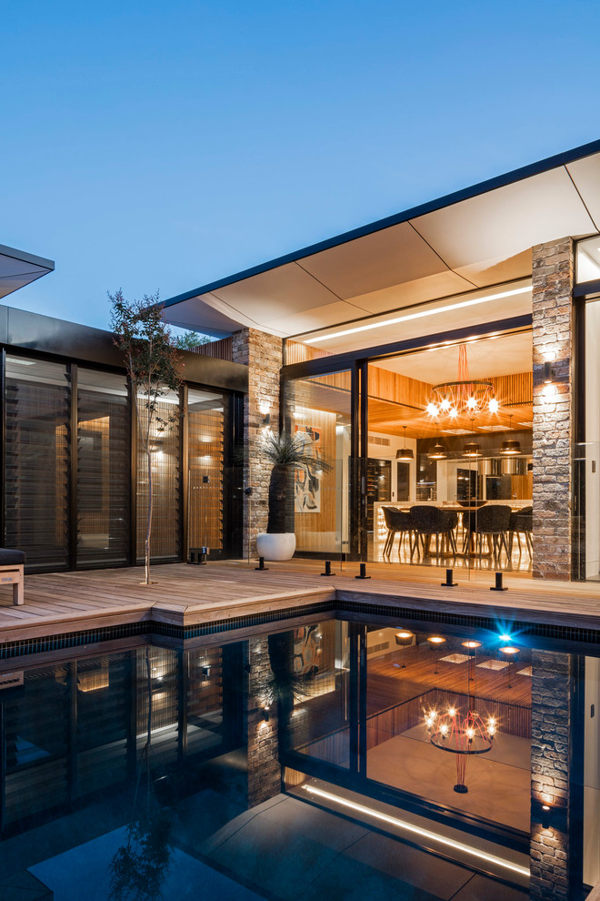 This is an example of a mid-sized contemporary backyard custom-shaped pool in Wollongong with decking.