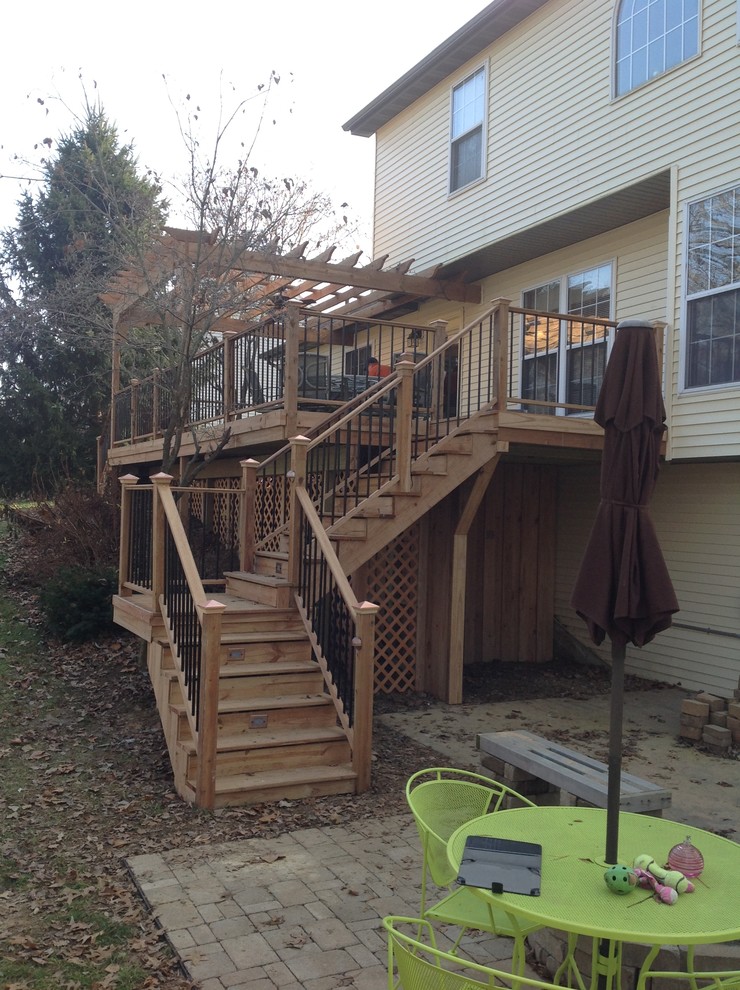 Example of a large transitional backyard deck design in St Louis with a pergola