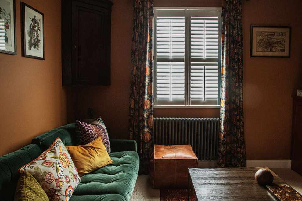 This is an example of an eclectic living room curtain in Kent with orange walls, carpet, a tiled fireplace surround, white floors, wallpapered walls and curtains.
