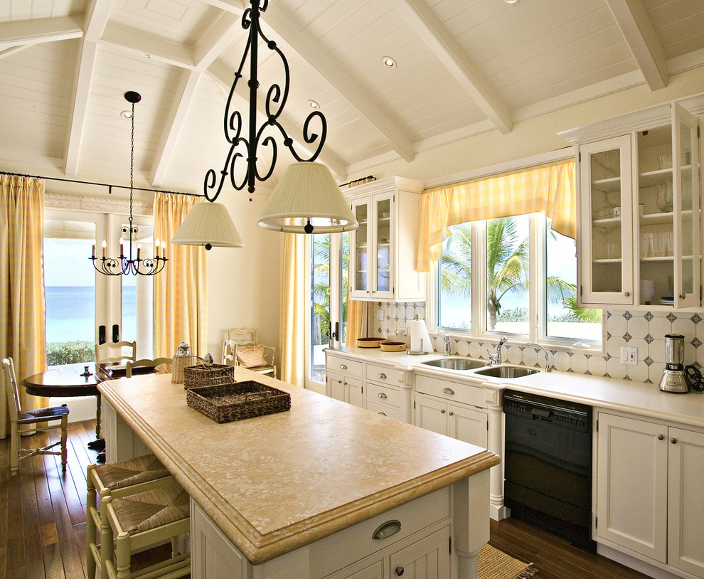 Tropical kitchen in Miami with beaded inset cabinets, a double-bowl sink, white cabinets and black appliances.