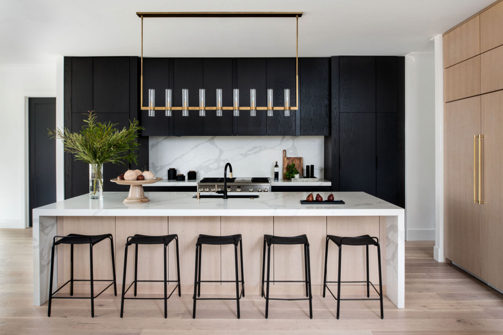 Design ideas for a contemporary l-shaped kitchen in DC Metro with an undermount sink, flat-panel cabinets, black cabinets, white splashback, stainless steel appliances, light hardwood floors, with island, beige floor and white benchtop.