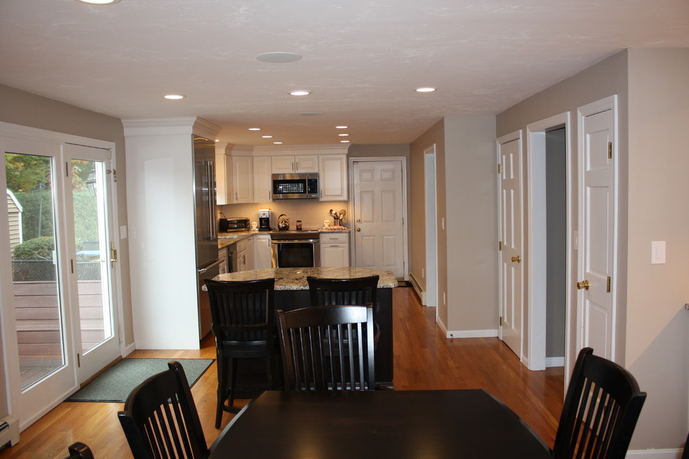Example of a large transitional l-shaped light wood floor eat-in kitchen design in Boston with an undermount sink, raised-panel cabinets, white cabinets, granite countertops, gray backsplash, ceramic backsplash, stainless steel appliances and an island