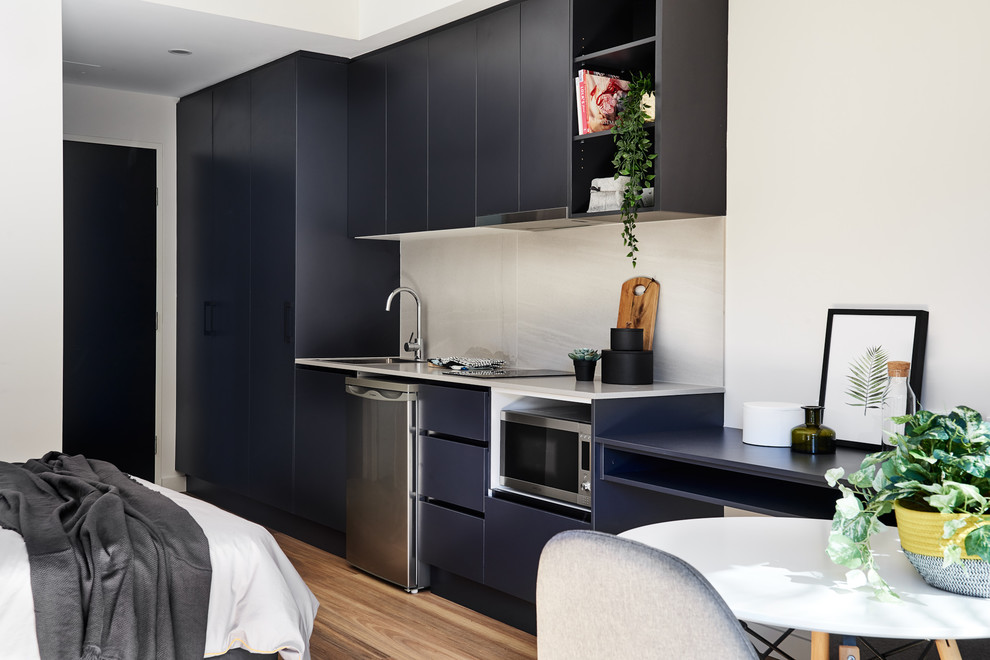 Photo of a small contemporary single-wall open plan kitchen in Sydney with a drop-in sink, black cabinets, quartz benchtops, grey splashback, porcelain splashback, stainless steel appliances, vinyl floors, no island and grey benchtop.