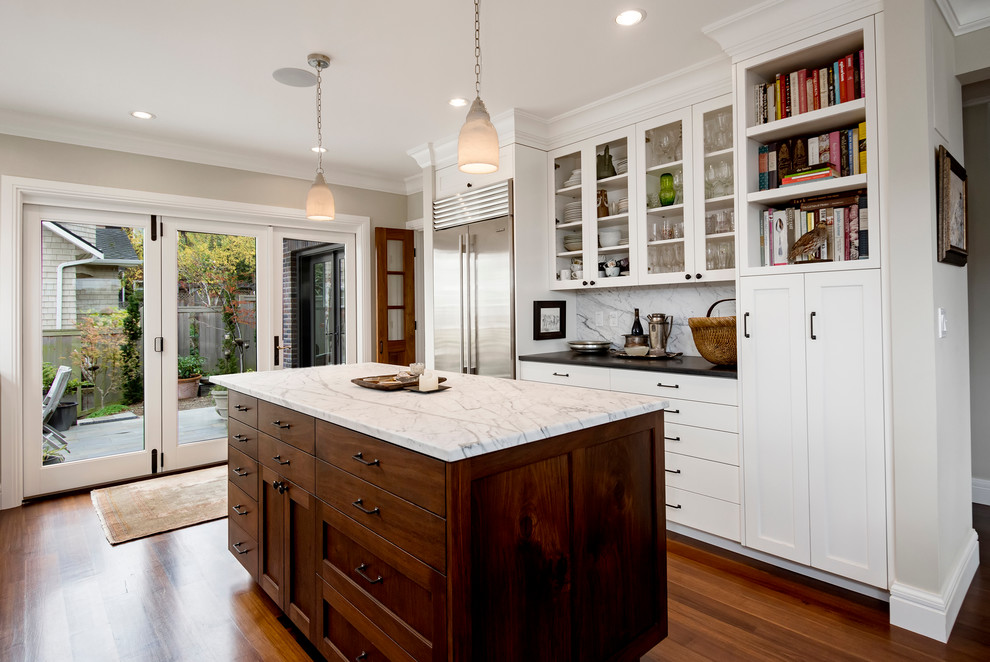 This is an example of a mid-sized traditional u-shaped separate kitchen in Seattle with shaker cabinets, white cabinets, marble benchtops, marble splashback, dark hardwood floors and with island.