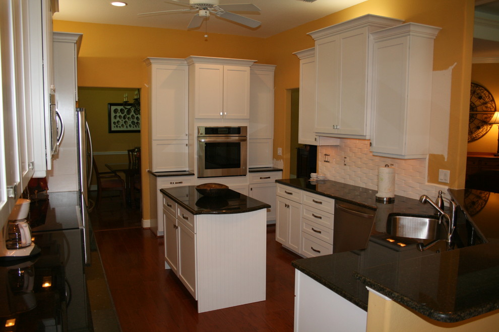 Inspiration for a modern eat-in kitchen remodel with an undermount sink, flat-panel cabinets, white cabinets, quartzite countertops, white backsplash, porcelain backsplash, stainless steel appliances and an island