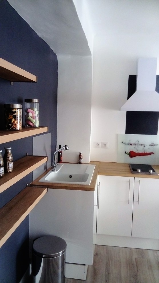 Inspiration pour cuisine ouverte in L With un évier 1 bac, des portes de placard blanches, un plan de travail en stratifié, un électroménager blanc, sol en stratifié, îlot, une crédence multicolore, une crédence en carreau de verre, un sol marron and un plan de travail beige.