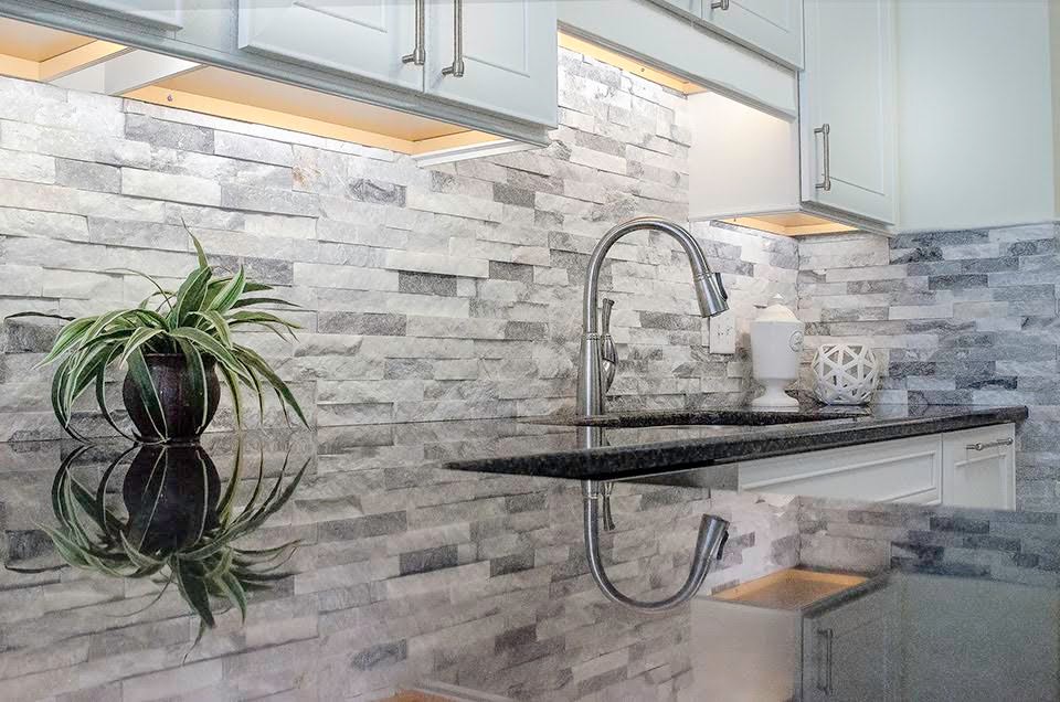 Example of a large transitional l-shaped kitchen design with an undermount sink, recessed-panel cabinets, white cabinets, granite countertops, gray backsplash, stone tile backsplash, stainless steel appliances and a peninsula