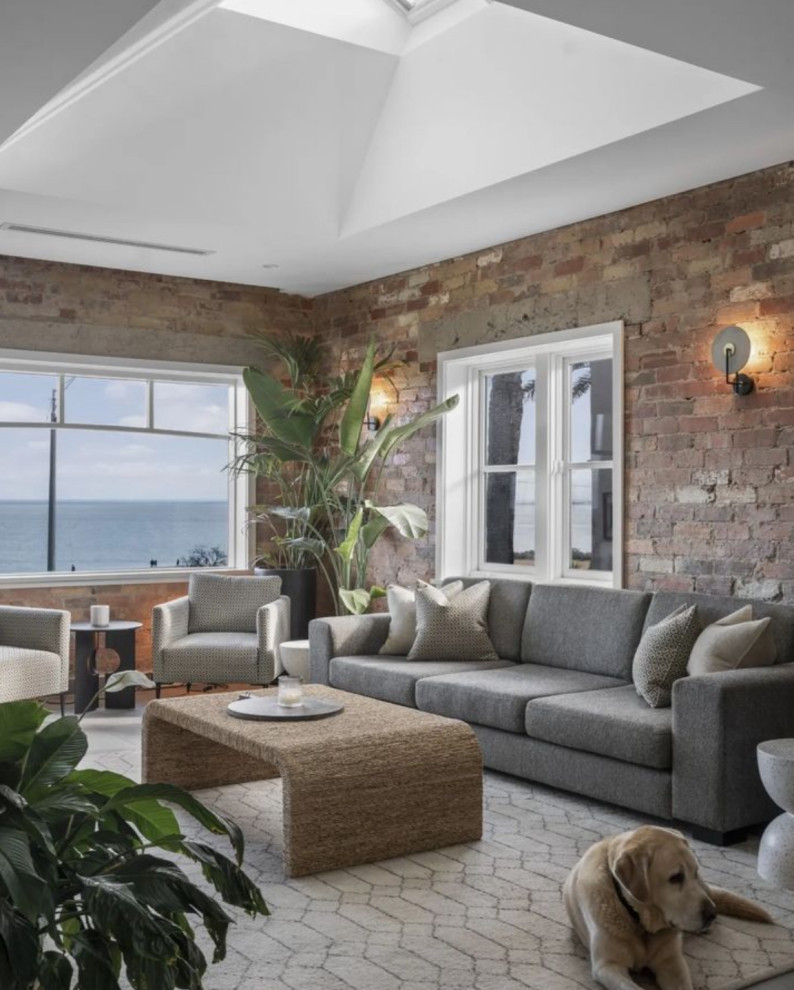 This is an example of a mid-sized contemporary open concept family room in Melbourne with porcelain floors, a standard fireplace, a brick fireplace surround, grey floor, vaulted and brick walls.