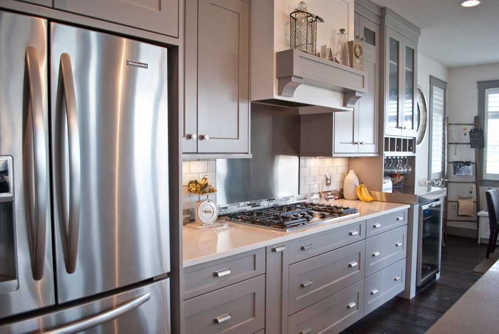 Inspiration for a large transitional l-shaped open concept kitchen remodel with an undermount sink, flat-panel cabinets, gray cabinets, quartzite countertops, white backsplash, subway tile backsplash, stainless steel appliances and an island