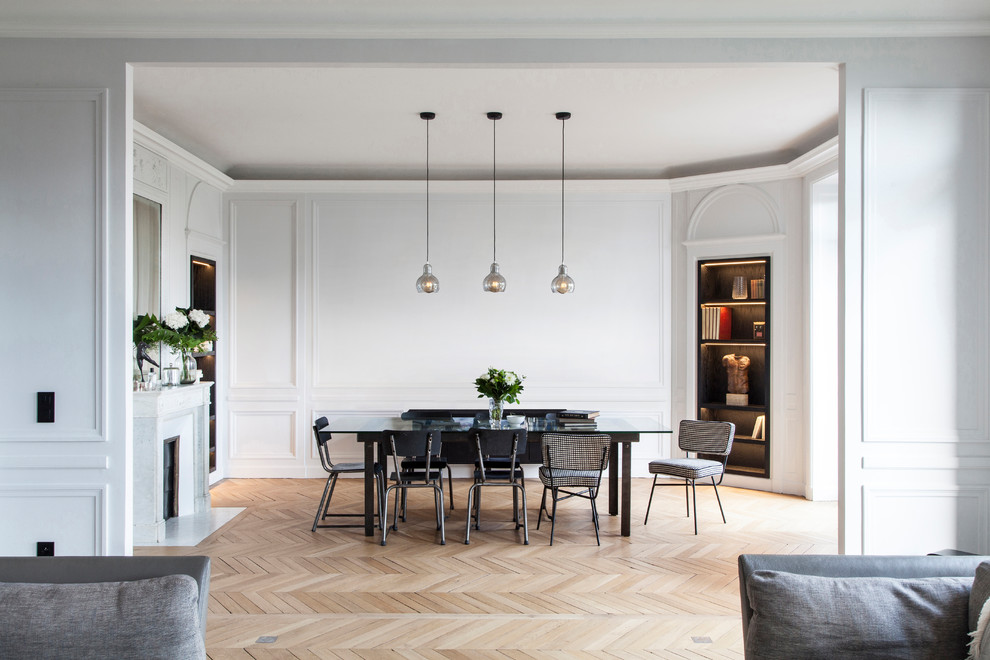 Photo of a large contemporary open plan dining in Paris with light hardwood floors, a standard fireplace, white walls, a stone fireplace surround and beige floor.